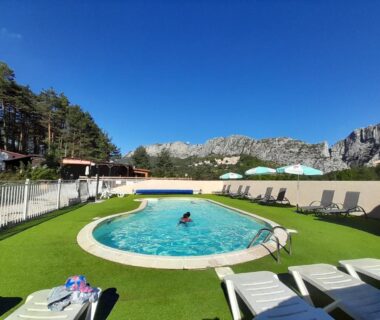 Piscine ronde et transats avec montagnes en arrière plan au Camping La Pinatelle