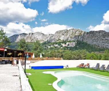Piscine extérieure et transats face aux falaises au Camping La Pinatelle