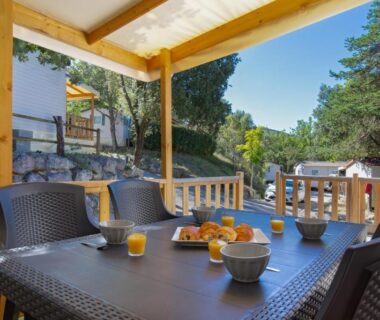 Terrasse ombragée avec table et chaises au Camping La Pinède