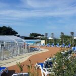 Bord de piscine avec bassin couvert et transats au Camping La Pointe du Talud