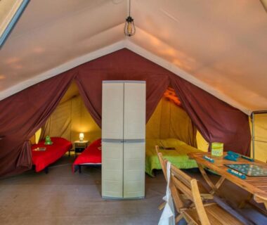 Dans tente aménagée avec lits et coin repas du Camping La Sagne
