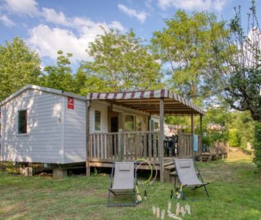 Mobil-home sur pelouse avec terrasse et chaises longues au Camping La Sagne