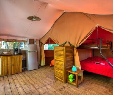 Intérieur de lodge en toile avec lits superposés et kitchenette au Camping La Sagne