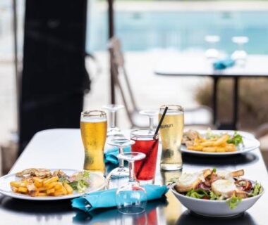 Terrasse au bord de la piscine avec plats et boissons au Camping La Tour de France
