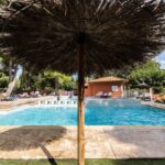 Bord de piscine avec parasol en paille au Camping La Tour de France