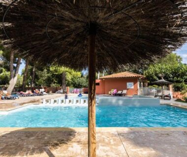 Bord de piscine avec parasol en paille au Camping La Tour de France