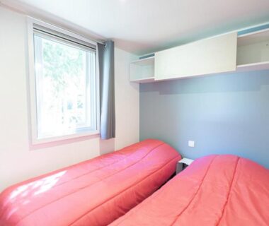 Chambre avec deux lits simples et fenêtre lumineuse dans le Camping La Venise Du Bocage