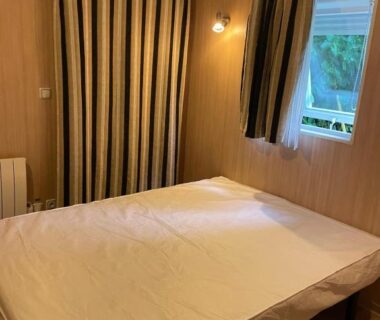 Intérieur chambre avec lit double et rideaux dans un hébergement du Camping La Venise Du Bocage