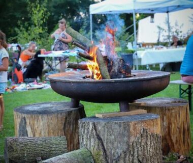 Espace extérieur avec brasero en métal et rondins pour s'asseoir au Camping La sablière