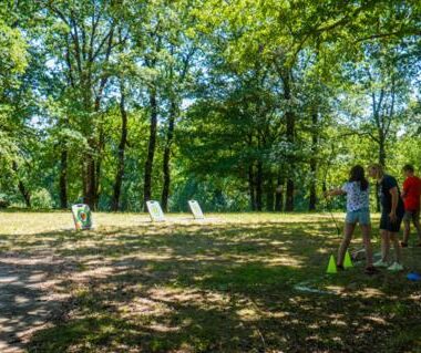Pelouse ombragée avec transats et personnes jouant au Camping Lac aux Oiseaux Mobil-home 3 pièces 4 personnes MAE-0991