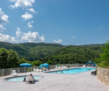 Piscine extérieure et transats avec vue sur collines au Camping Lac de Villefort