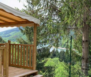 Terrasse en bois et voile d'ombrage avec vue sur le lac au Camping Lac de Villefort