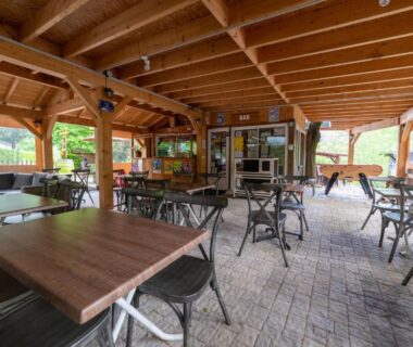Terrasse couverte avec tables et chaises au Camping Le Barutel