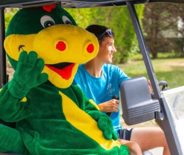 Sur le camping mascotte en costume dans un véhicule avec animatrice au Camping Le Bois Soleil mobilhome 3 pièces