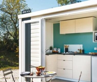Terrasse avec table et chaises devant kitchenette ouverte au camping Le Bois Verdon
