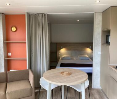 Séjour avec kitchenette, table et lit dans le cottage 2 pers du Camping Le Bon Coin