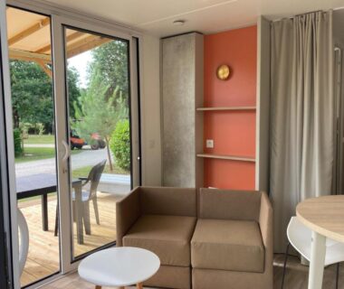 Séjour avec canapé et terrasse donnant sur pelouse du Camping Le Bon Coin Cottage 2 pers