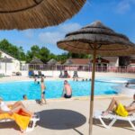 Piscine extérieure avec parasols et transats au Camping Le Both d'Orouet