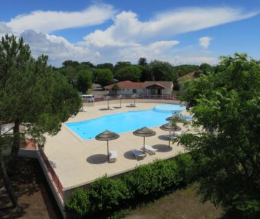 Espace piscine avec parasols et solarium au Camping Le Both d'Orouet