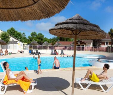 Piscine extérieure avec parasols et transats au Camping Le Both d'Orouet