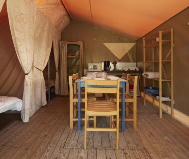 Intérieur de tente avec table et lits au Camping Le Both d'Orouet