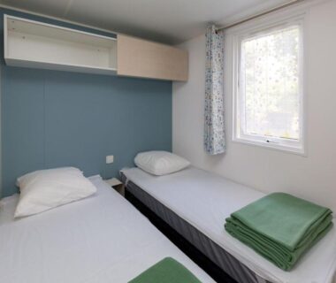 Chambre avec deux lits et linge plié dans le Camping Le Both d'Orouet