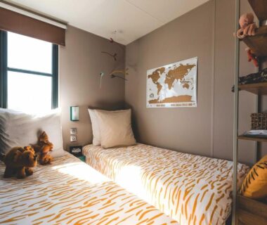 Chambre intérieure avec deux lits et carte du monde au Camping Le Braou Maeva