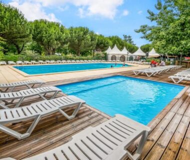 Piscines extérieures avec transats sur terrasse en bois au Camping Le Braou Maeva