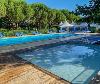 Piscine extérieure avec pataugeoire et chaises longues sur deck en bois au Camping Le Braou - Maeva