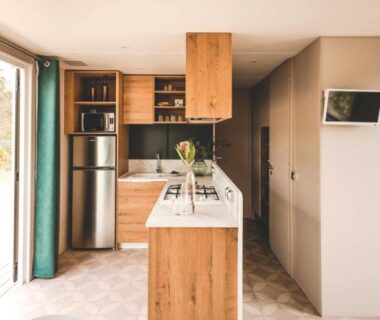 Intérieur de mobil home avec kitchenette îlot et baie vitrée dans le Camping Le Braou – Maeva