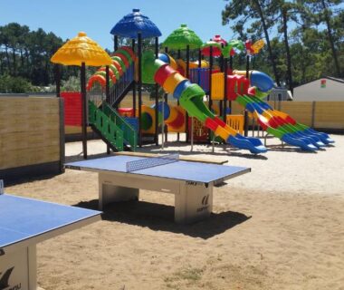 Aire de jeux colorée avec toboggans et tables de ping pong au Camping Le California