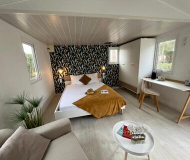 Intérieur de chambre avec lit double canapé et bureau au Camping Le Calypso 5 étoiles