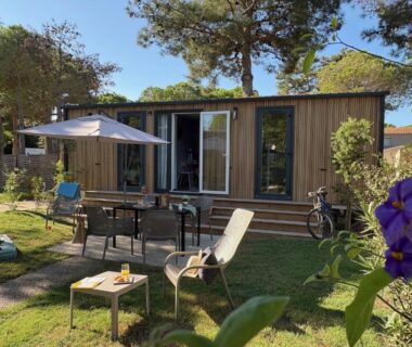 Terrasse et jardin avec table chaises parasol et transat au Camping Le Calypso 5 étoiles