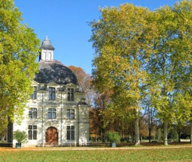 Façade d'un manoir entourée d'arbres au Camping Le Cardinal