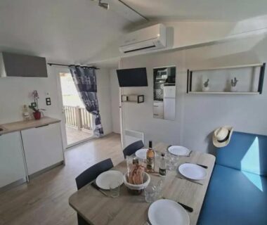 Intérieur avec table dressée et coin cuisine dans le mobil-home du Camping Le Chassezac