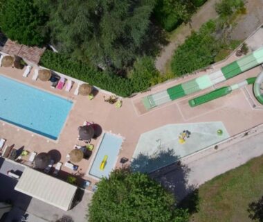 Vue aérienne de piscines toboggan et bains de soleil au Camping Le Chassezac