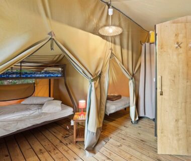 Intérieur de tente glamping avec lits en bois et armoire du Camping Le Damier