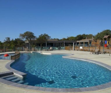 Bord de piscine avec transats et terrasse au Camping Le Damier