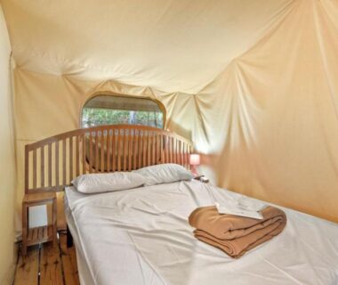 Intérieur de tente avec lit et serviettes au Camping Le Damier