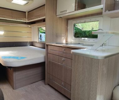 Intérieur de caravane avec lit et kitchenette au Camping Le Douzou