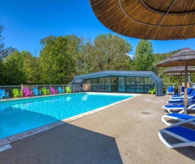 Piscine extérieure avec transats et parasols au Camping Le Douzou