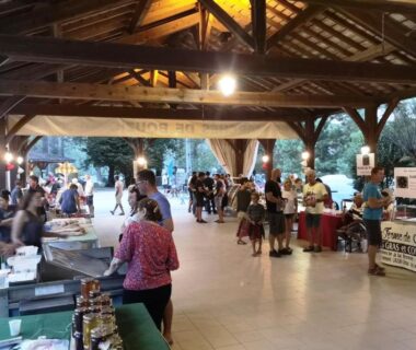 Sous un abri couvert avec stands et visiteurs au Camping Le Douzou