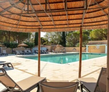 Bord de piscine avec transats sous paillote au camping Le Hameau des Pins