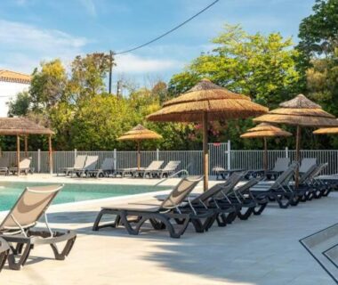 Bord de piscine avec transats et parasols au Camping Le Hameau des Pins