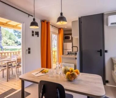 Intérieur avec table à manger et terrasse bois visible dans le mobil-home Le Hameau des Pins