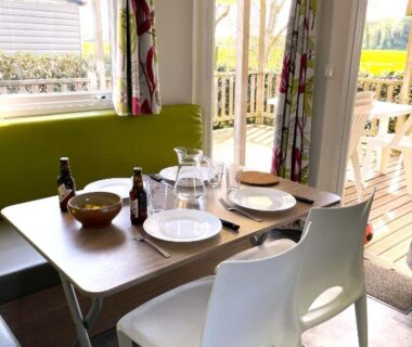 Intérieur coin repas avec table dressée et terrasse extérieure au Camping Le Jaunay ST GILLES-CROIX-DE-VIE