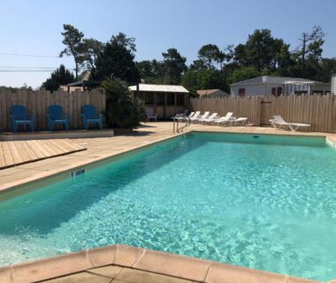 Piscine extérieure avec transats et mobil-homes au Camping Le Logis 3 étoiles