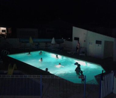 Piscine extérieure nocturne avec baigneurs dans l'eau au Camping Le Logis 3 étoiles