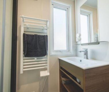 Salle de bains avec lavabo et radiateur porte-serviettes au Camping Le Malazéou Wellness Sport Camping