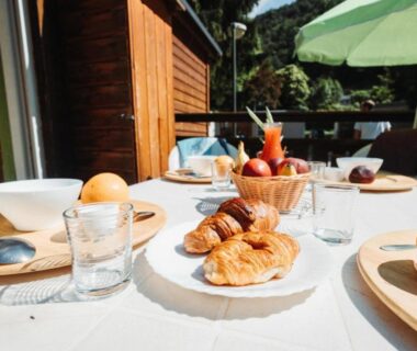 Terrasse extérieure avec croissants fruits et vaisselle au Camping Le Malazéou Wellness Sport Camping